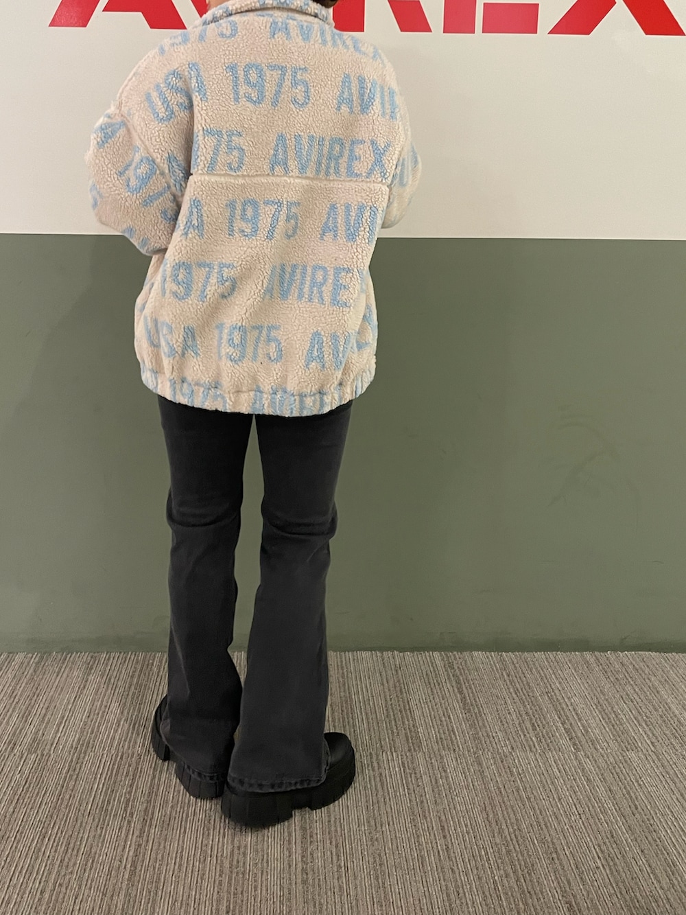 ブラック系のデニムパンツ、ベージュ系のブルゾン、レッド系のニット/セーターを着用したレディースの秋コーディネートの2枚目の写真