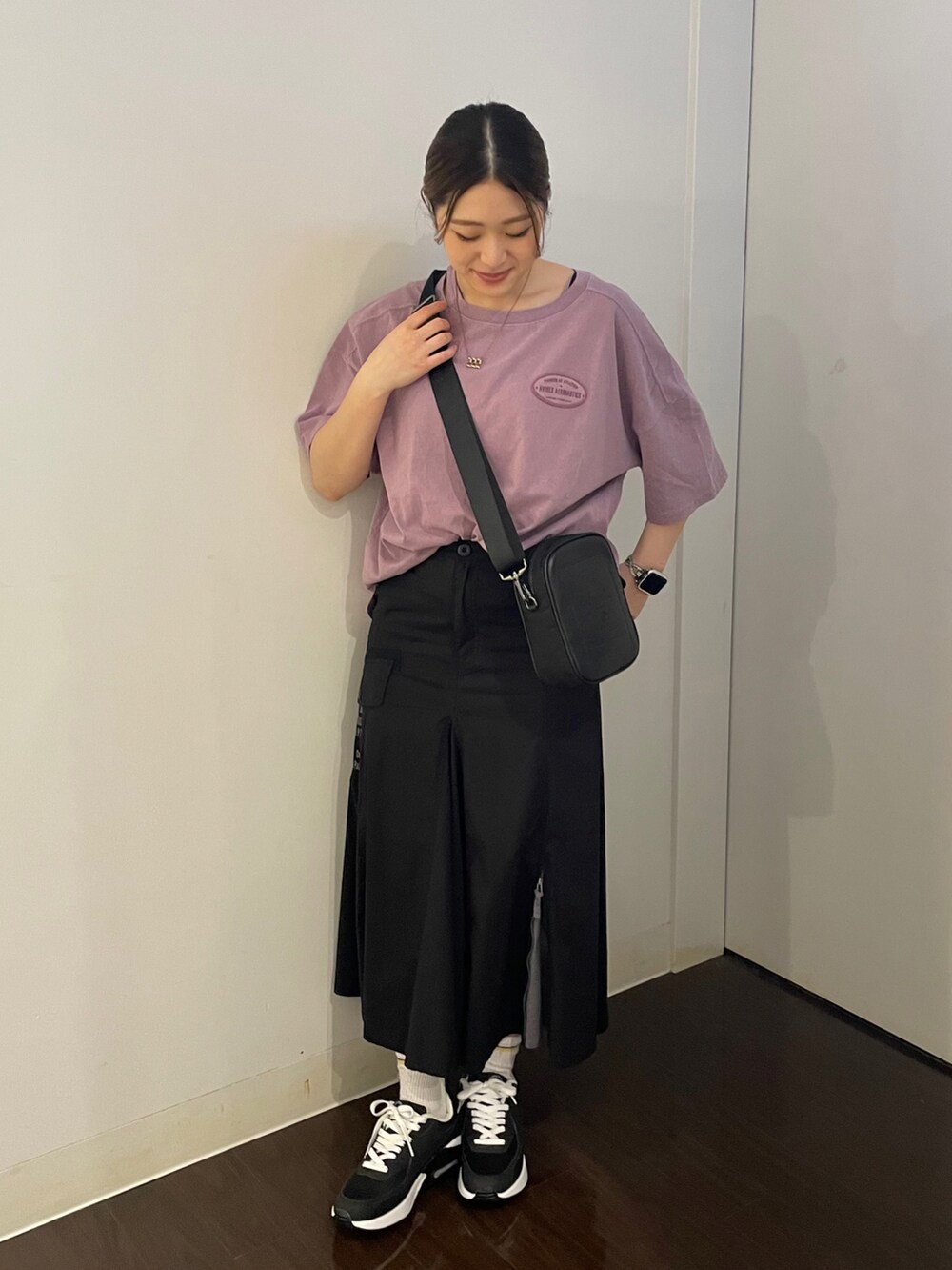 ブラック系のスカート、パープル系のTシャツ/カットソー、ブラック系のスニーカーを着用したレディースの夏コーディネートの2枚目の写真