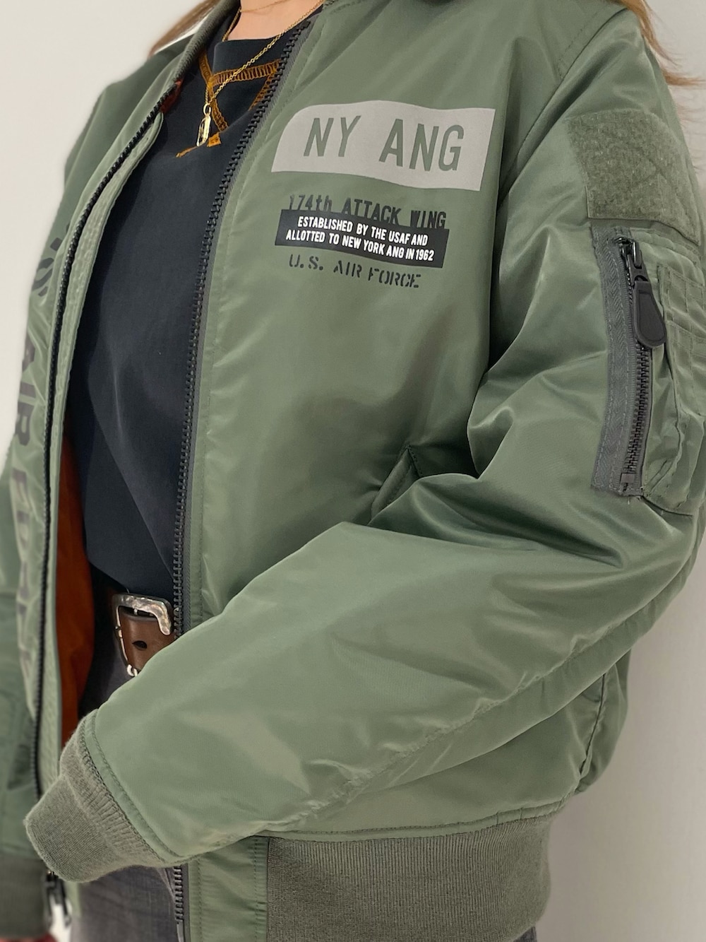 ブルー系のデニムパンツ、グリーン系のMA-1、ブラック系のTシャツ/カットソーを着用したレディースの夏コーディネートの3枚目の写真