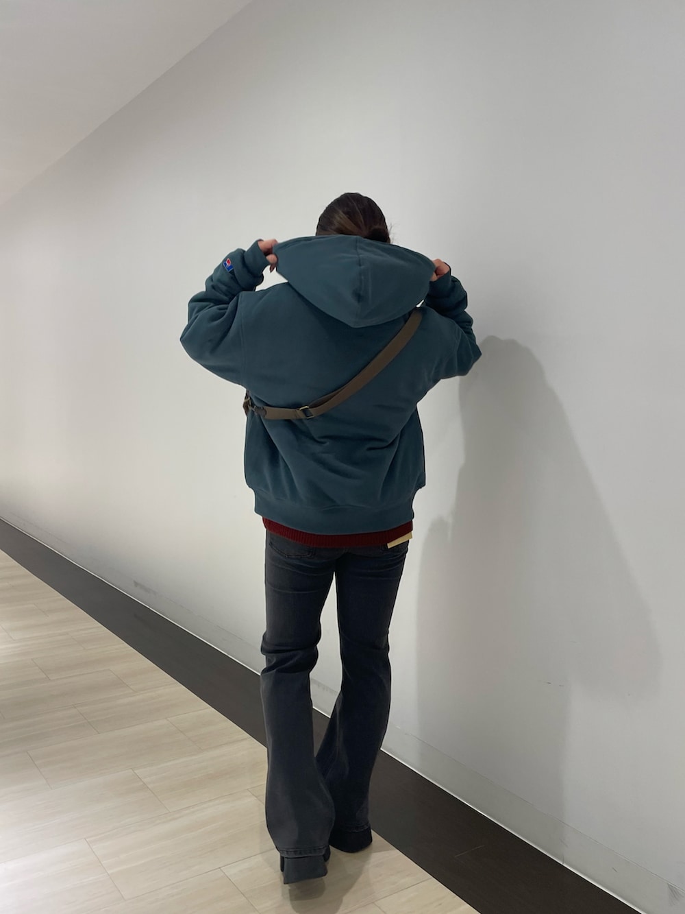 ブラック系のデニムパンツ、レッド系のニット/セーター、グリーン系のパーカーを着用したレディースの秋コーディネートの2枚目の写真