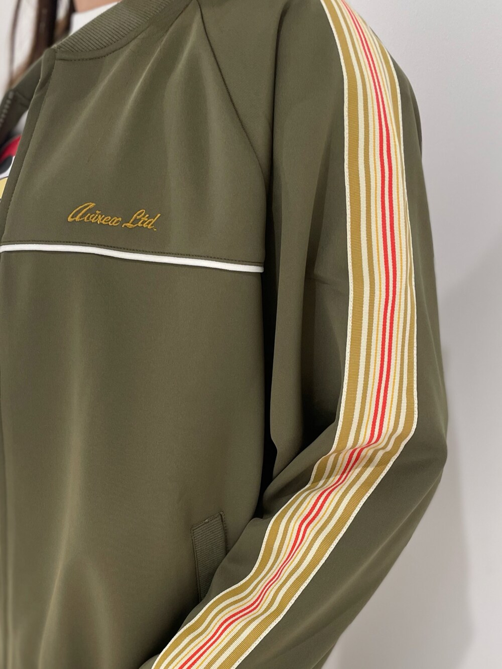 グリーン系のスカート、ホワイト系のTシャツ/カットソー、グリーン系のジャージを着用したレディースの春コーディネートの2枚目の写真