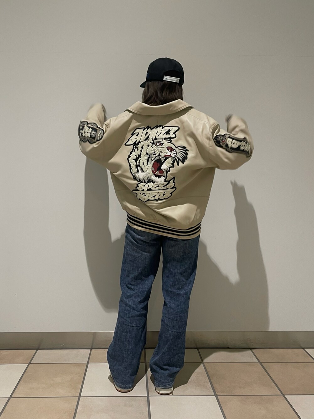 ホワイト系のスタジャン、ブラック系のTシャツ/カットソー、ブラック系のキャップを着用したレディースの秋コーディネートの2枚目の写真