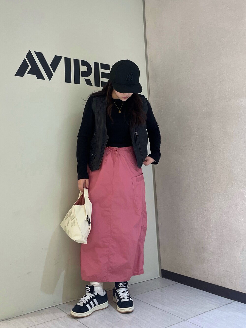 グレー系のショルダーバッグ、ブラック系のその他アウター、ピンク系のスカートを着用したレディースの冬コーディネートの2枚目の写真