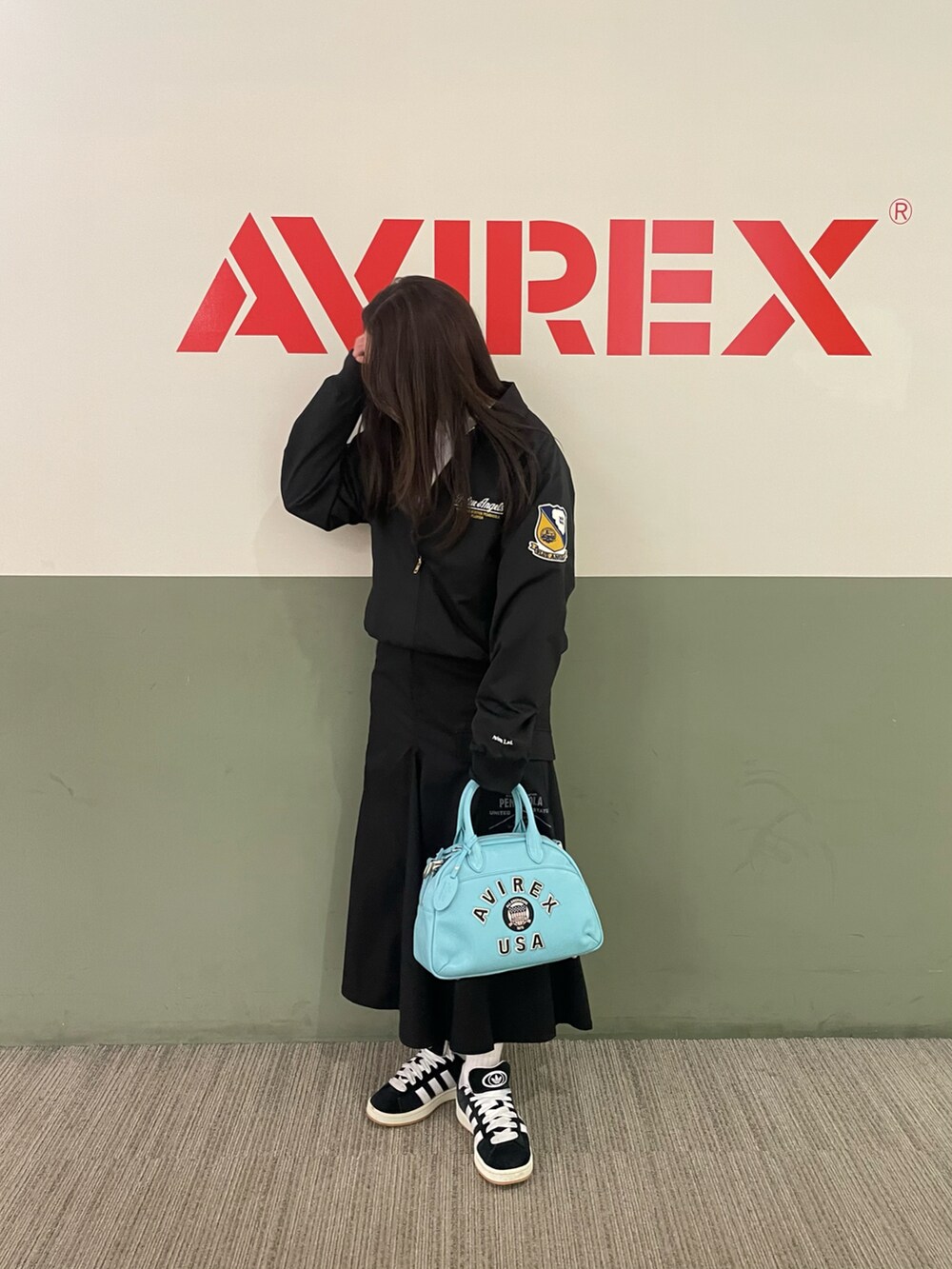 ブラック系のミリタリージャケット、ブラック系のスカート、その他のボストンバッグを着用したレディースの春コーディネートの2枚目の写真