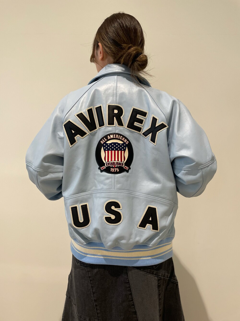 ブルー系のスタジャン、ブラック系のデニムスカート、ホワイト系のTシャツ/カットソーを着用したレディースの秋コーディネートの3枚目の写真