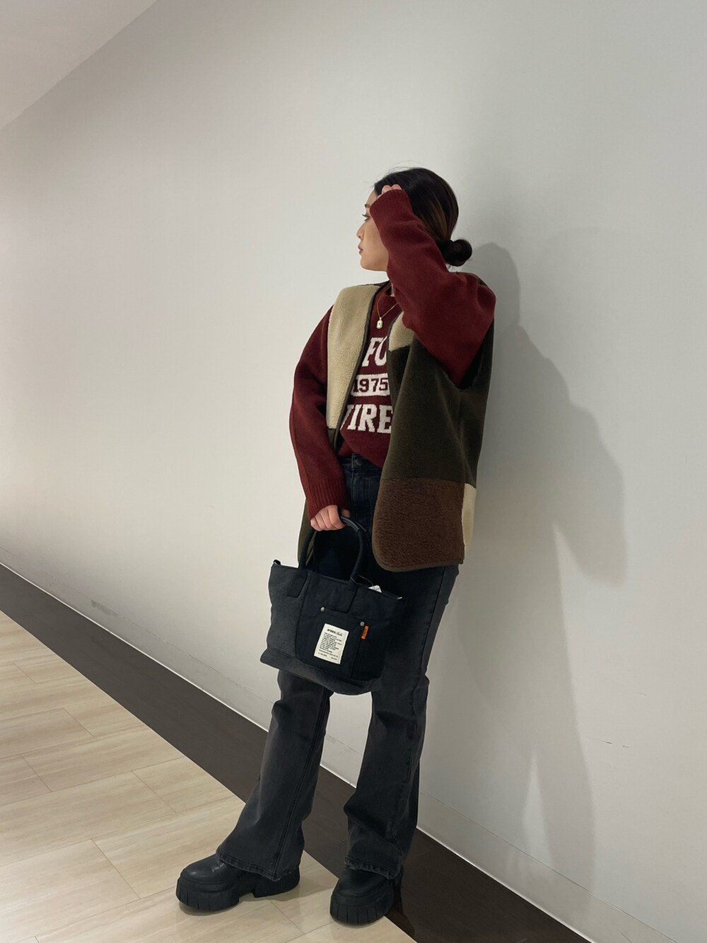 レッド系のニット/セーター、ブラック系のトートバッグ、ブラック系のデニムパンツを着用したレディースの秋コーディネートの2枚目の写真
