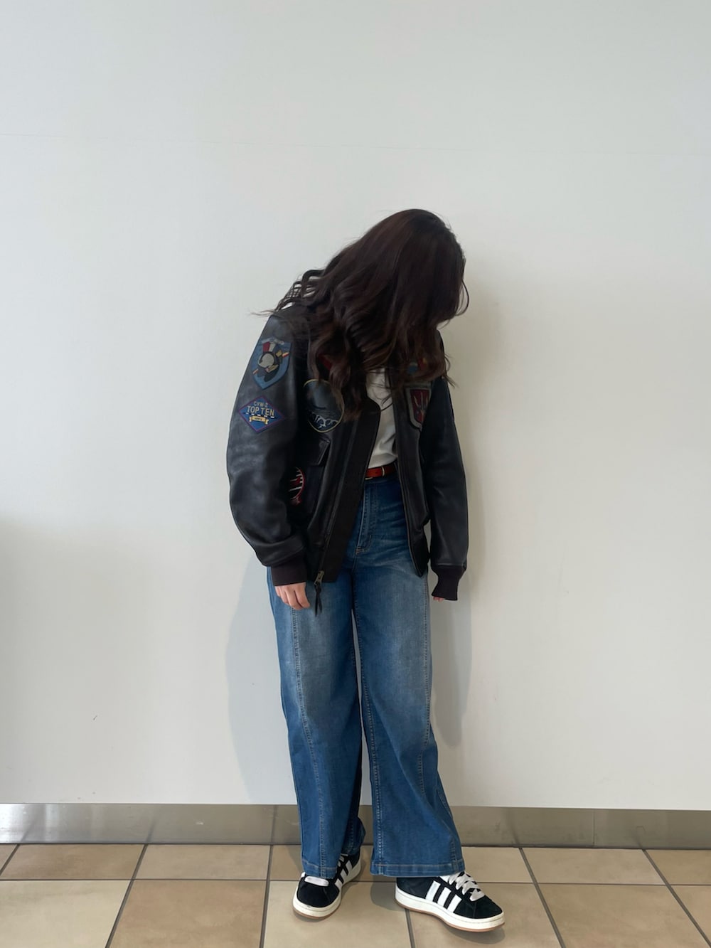 ブルー系のデニムパンツ、ブラウン系のミリタリージャケット、イエロー系のベルトを着用したレディースの春コーディネートの2枚目の写真