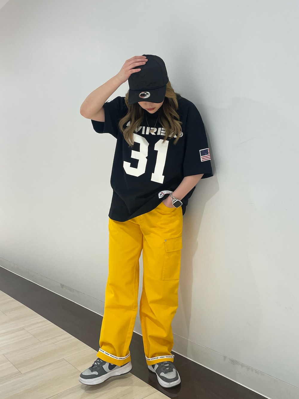 ブラック系のTシャツ/カットソー、イエロー系のカーゴパンツ、ブラック系のキャップを着用したレディースの春コーディネートの2枚目の写真