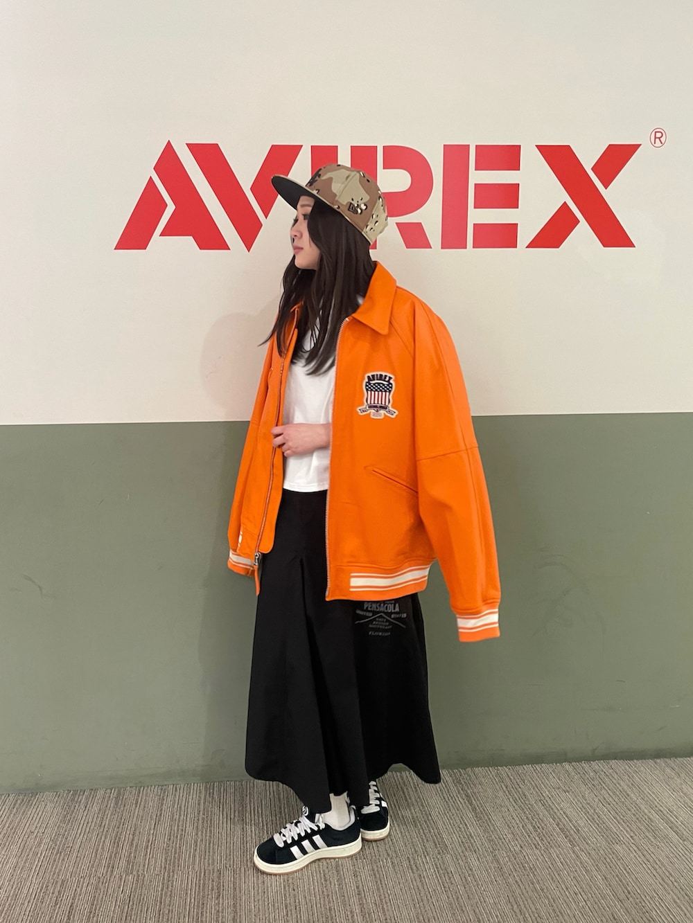 オレンジ系のスタジャン、ブラック系のスカート、ホワイト系のTシャツ/カットソーを着用したレディースの冬コーディネートの2枚目の写真