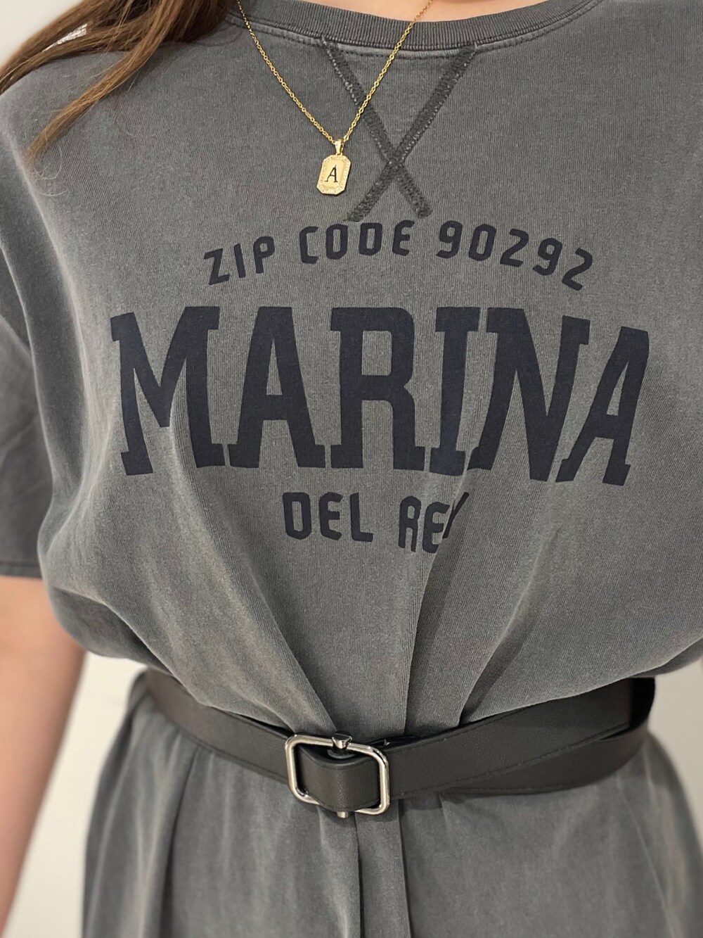 ブラック系のショルダーバッグ、グレー系のワンピース、グリーン系のスカートを着用したレディースの春コーディネートの2枚目の写真