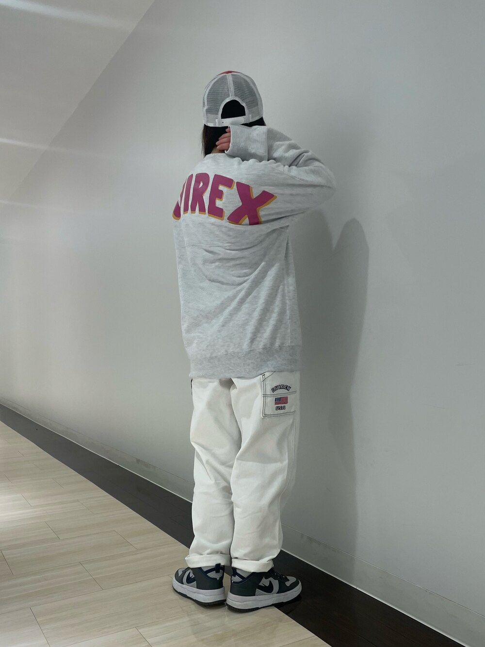 ホワイト系のデニムパンツ、グレー系のスウェット、オレンジ系のハットを着用したレディースの冬コーディネートの2枚目の写真