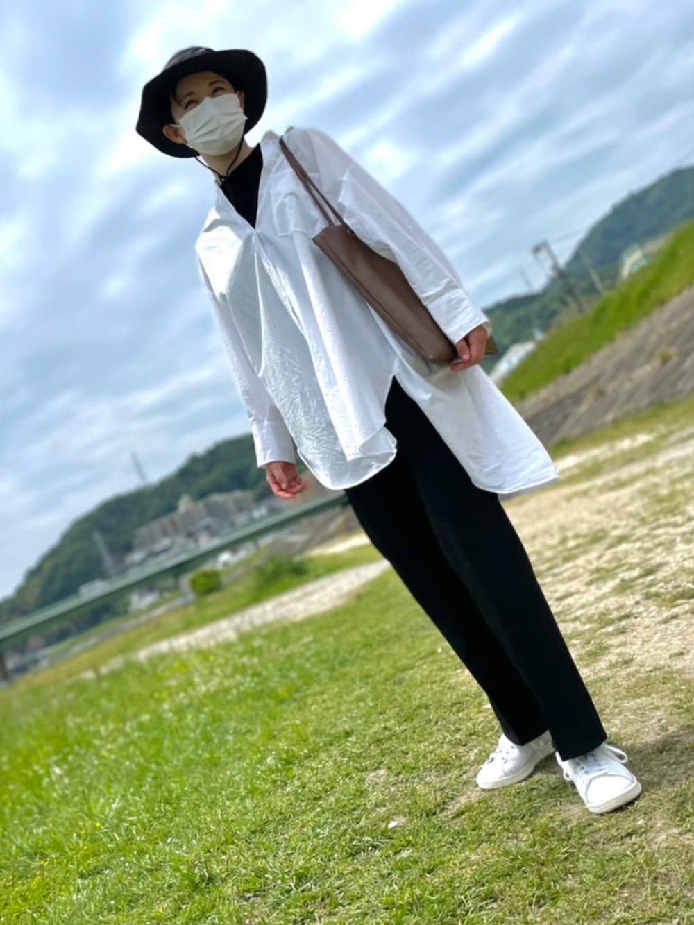 ブラック系のスラックス、ホワイト系のシャツ/ブラウス、ブラウン系のトートバッグを着用したレディースの春コーディネートの2枚目の写真