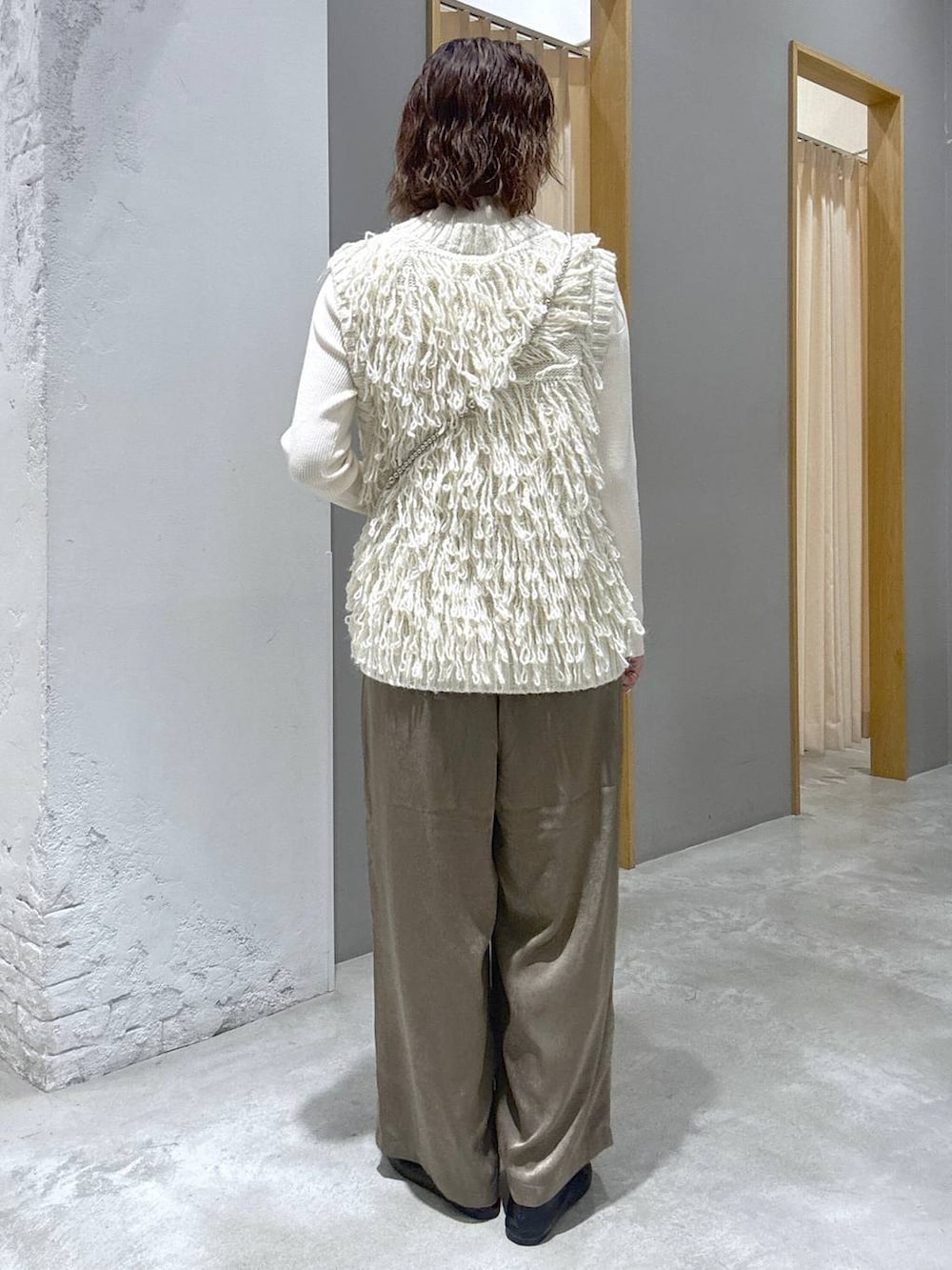 ホワイト系のニット/セーター、ホワイト系のベスト、グレー系のショルダーバッグを着用したレディースの秋コーディネートの3枚目の写真