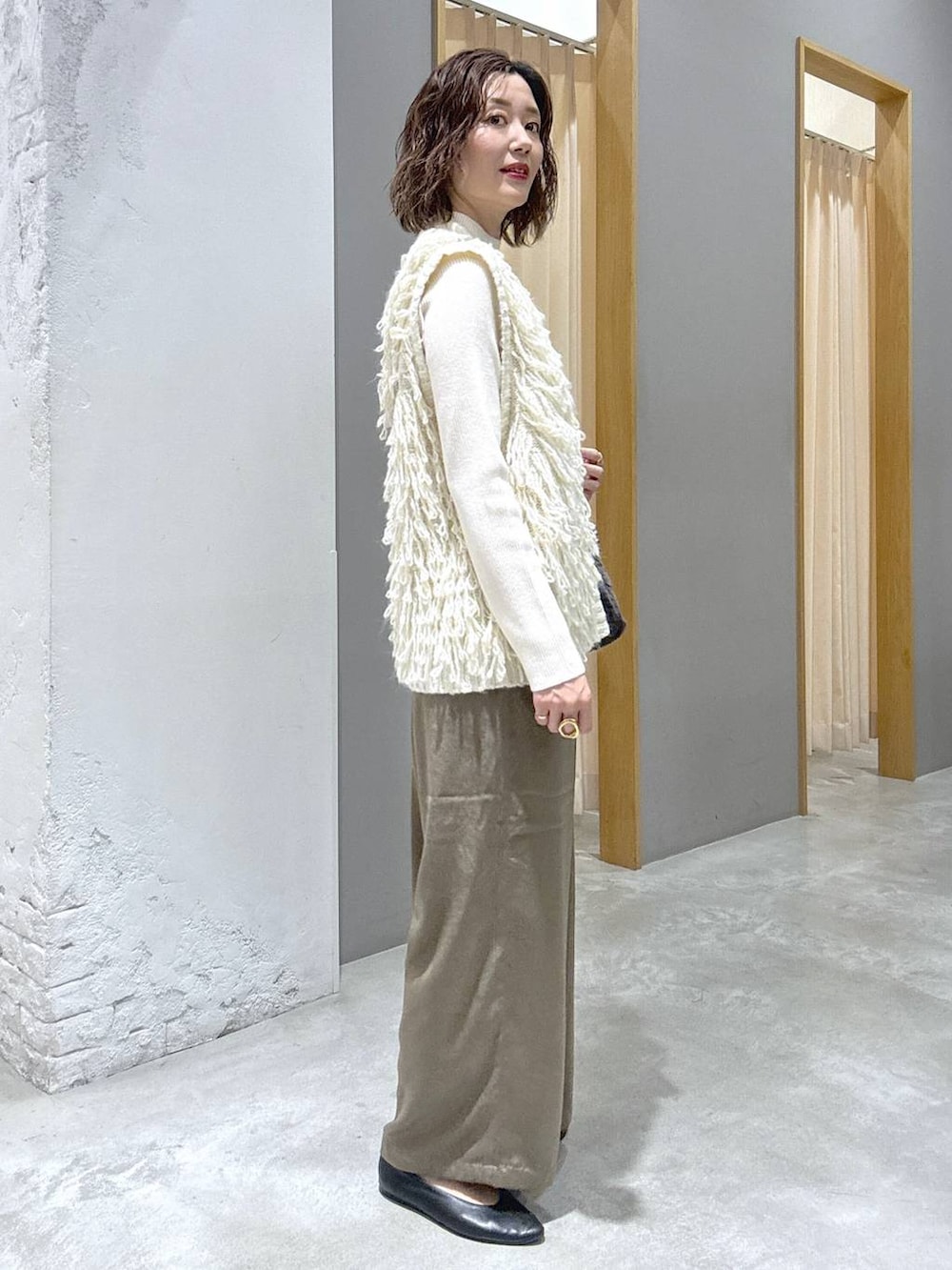 ホワイト系のニット/セーター、ホワイト系のベスト、グレー系のショルダーバッグを着用したレディースの秋コーディネートの2枚目の写真