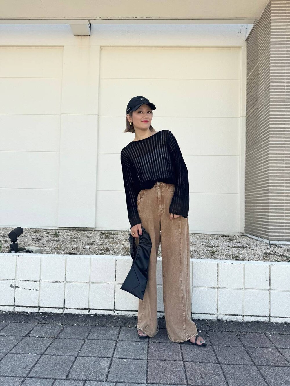 ブラック系のサンダル、ブラウン系のデニムパンツ、ブラック系のニット/セーターを着用したレディースの秋コーディネートの2枚目の写真