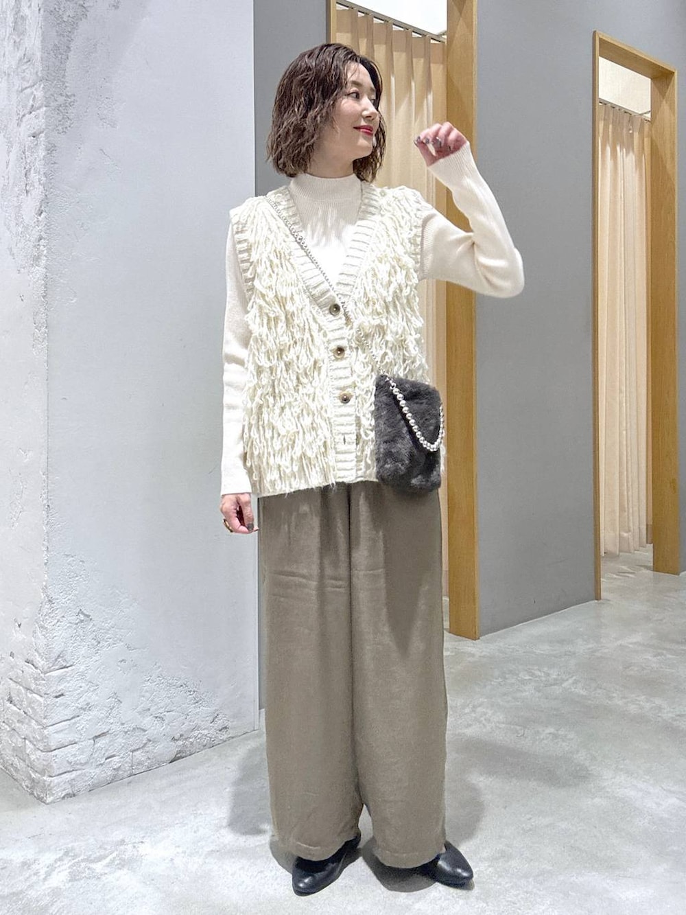ホワイト系のニット/セーター、ホワイト系のベスト、グレー系のショルダーバッグを着用したレディースの秋コーディネートの4枚目の写真