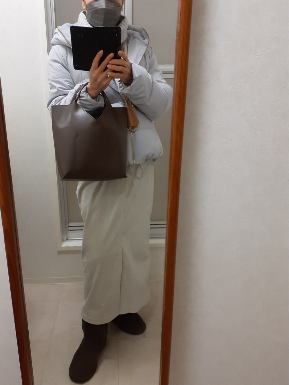 グレー系のニット/セーター、ホワイト系のスカート、ベージュ系のブーツを着用したレディースの冬コーディネートの2枚目の写真