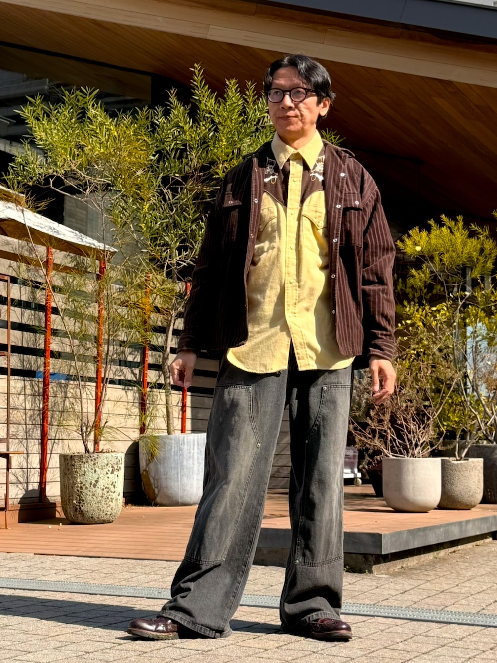 イエロー系のシャツ/ブラウス、ブラウン系のジャケット/アウター、グレー系のデニムパンツを着用したメンズの春コーディネートの2枚目の写真