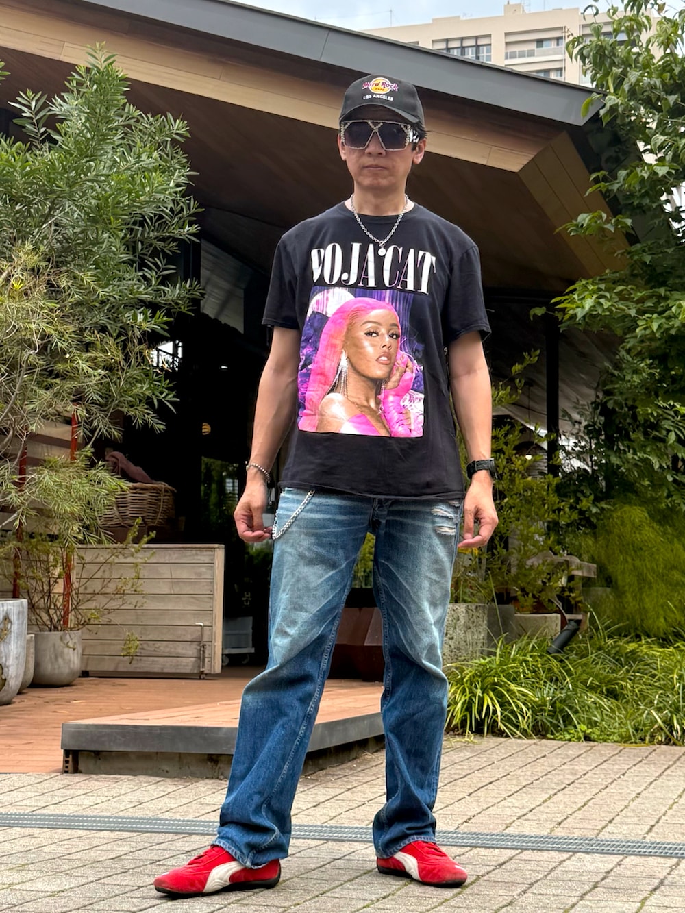 レッド系のスニーカー、ブラック系のTシャツ/カットソー、ブルー系のデニムパンツを着用したメンズの夏コーディネートの2枚目の写真