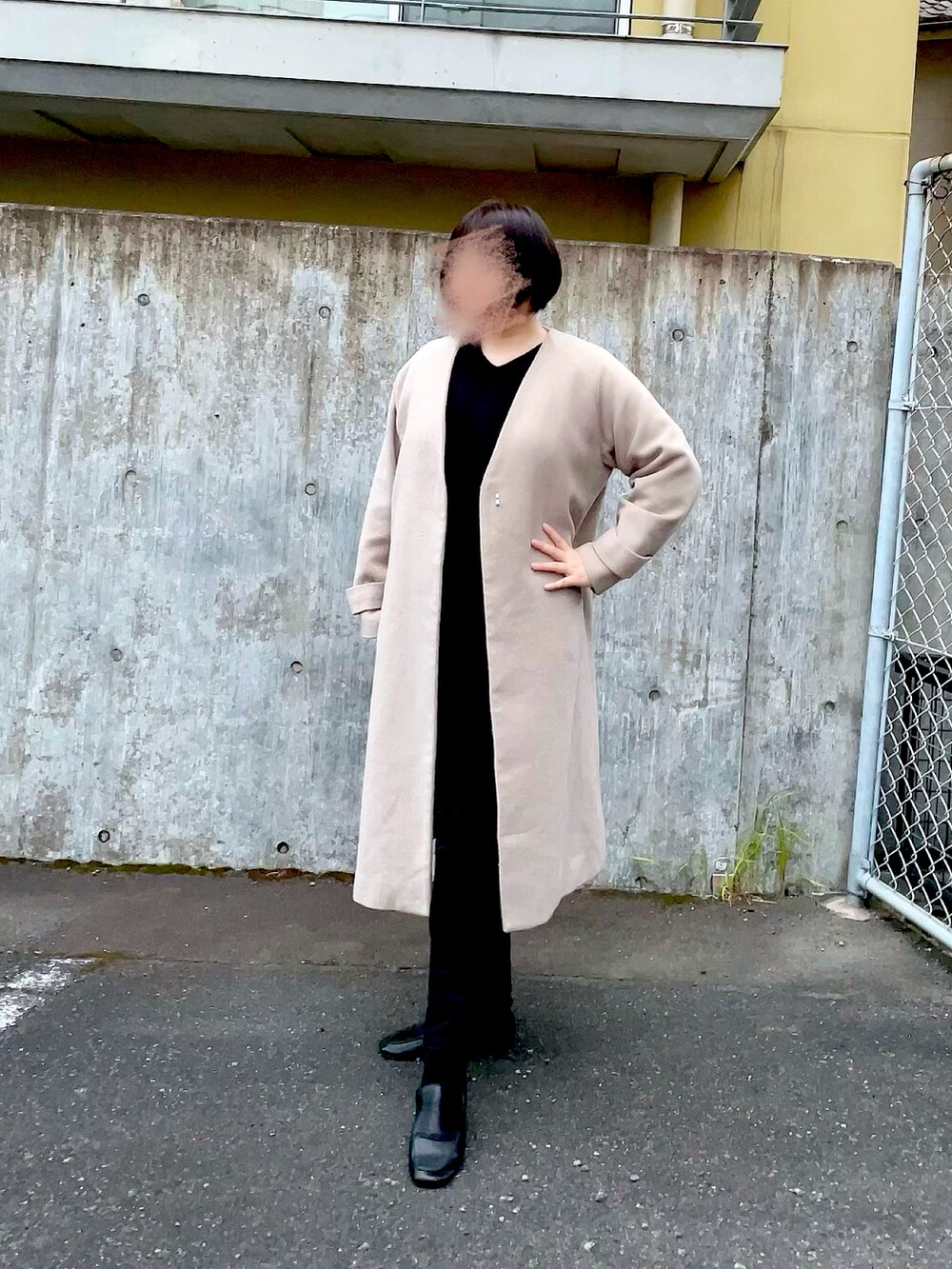 ベージュ系のノーカラーコート、ブラック系のニット/セーター、ブラック系のデニムパンツを着用したレディースの秋コーディネートの3枚目の写真