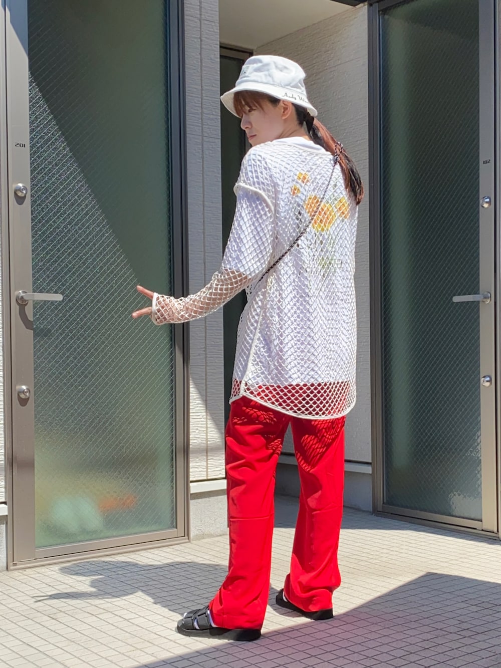 ホワイト系のTシャツ/カットソー、レッド系のその他パンツ、ブラック系のサンダルを着用したレディースの夏コーディネートの2枚目の写真