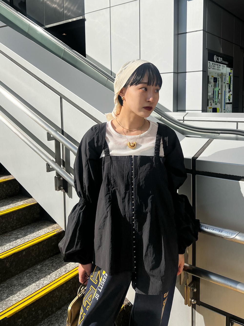 ブルー系のスウェットパンツ、ゴールド系のハンドバッグ、ブラック系のシャツ/ブラウスを着用したレディースの春コーディネートの3枚目の写真