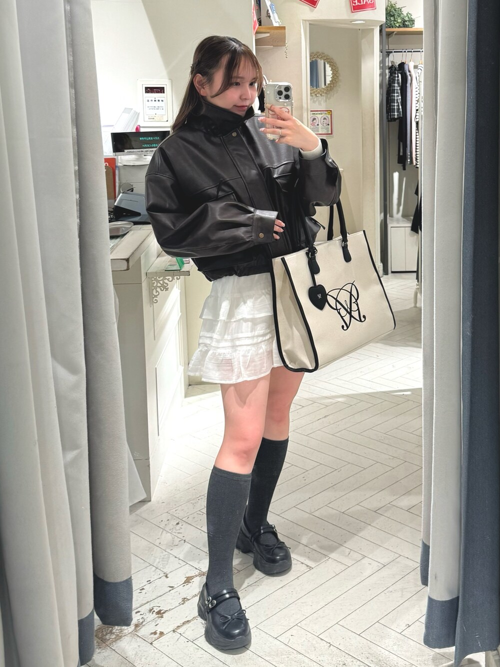 ホワイト系のスカート、ブラウン系のブルゾン、ホワイト系のトートバッグを着用したレディースの冬コーディネートの7枚目の写真