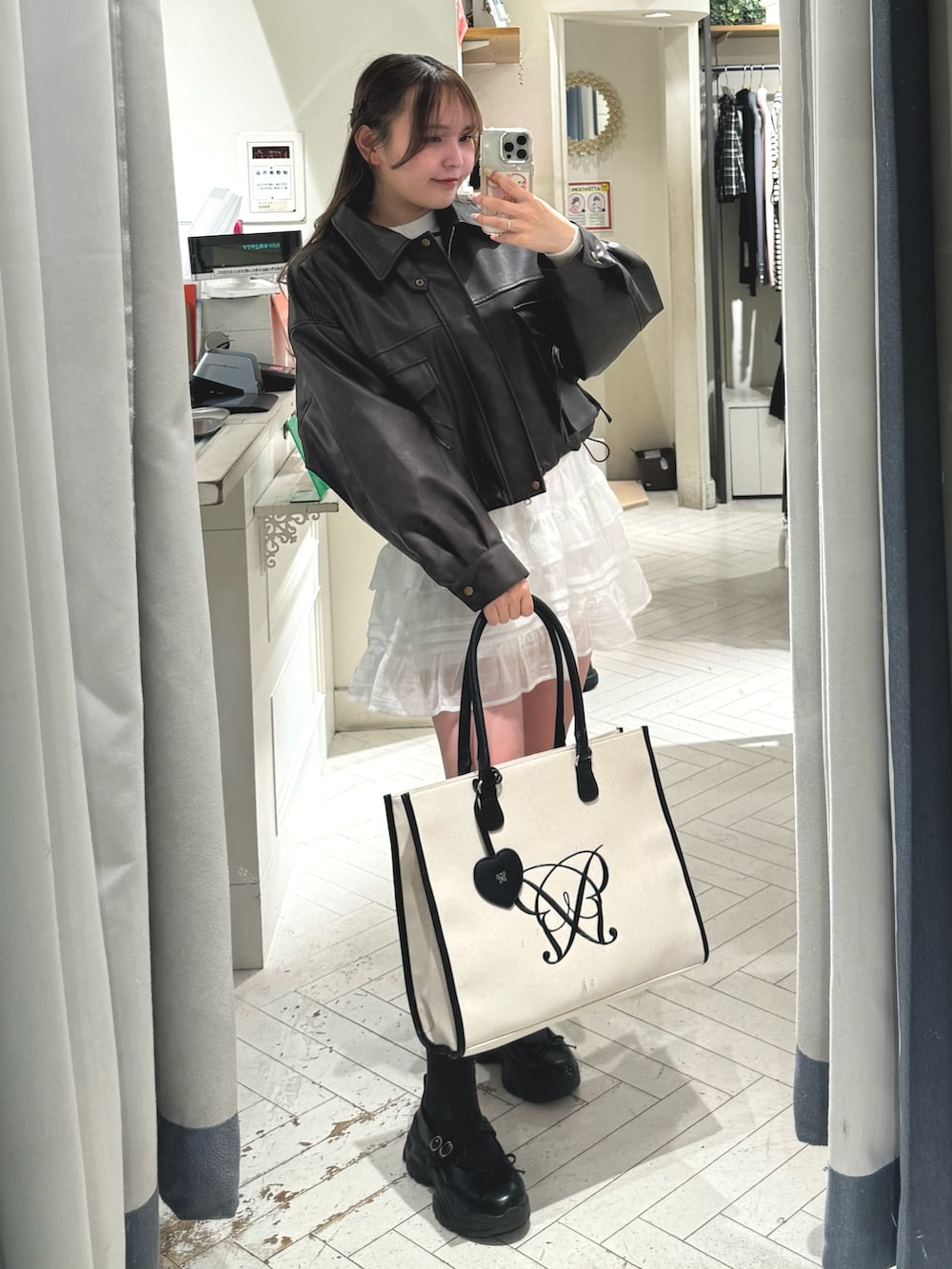 ホワイト系のスカート、ブラウン系のブルゾン、ホワイト系のトートバッグを着用したレディースの冬コーディネートの3枚目の写真