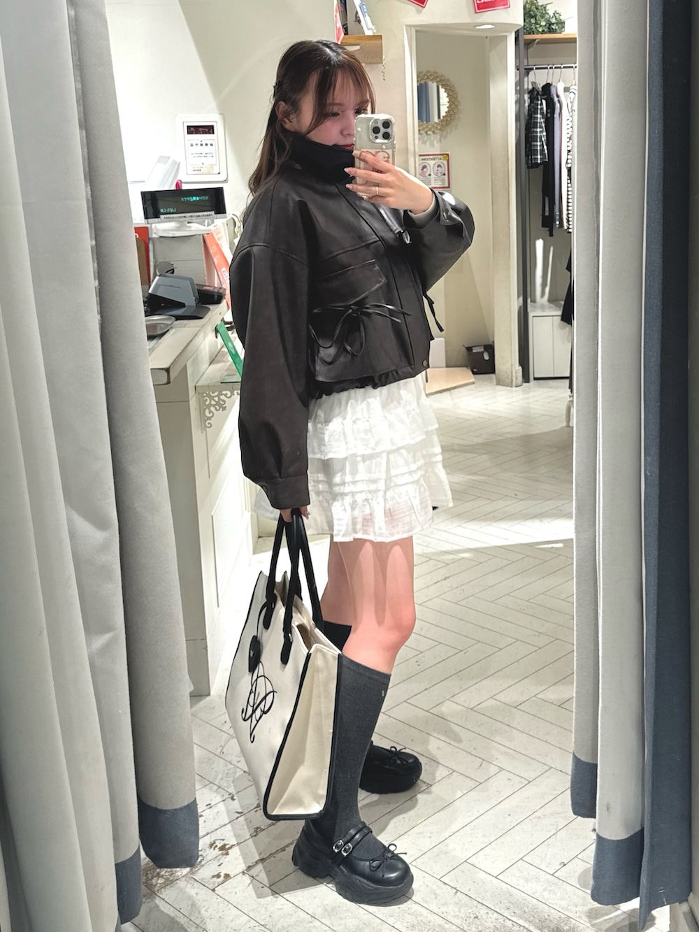 ホワイト系のスカート、ブラウン系のブルゾン、ホワイト系のトートバッグを着用したレディースの冬コーディネートの2枚目の写真