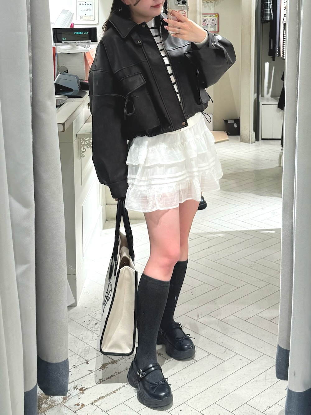 ホワイト系のスカート、ブラウン系のブルゾン、ホワイト系のトートバッグを着用したレディースの冬コーディネートの4枚目の写真