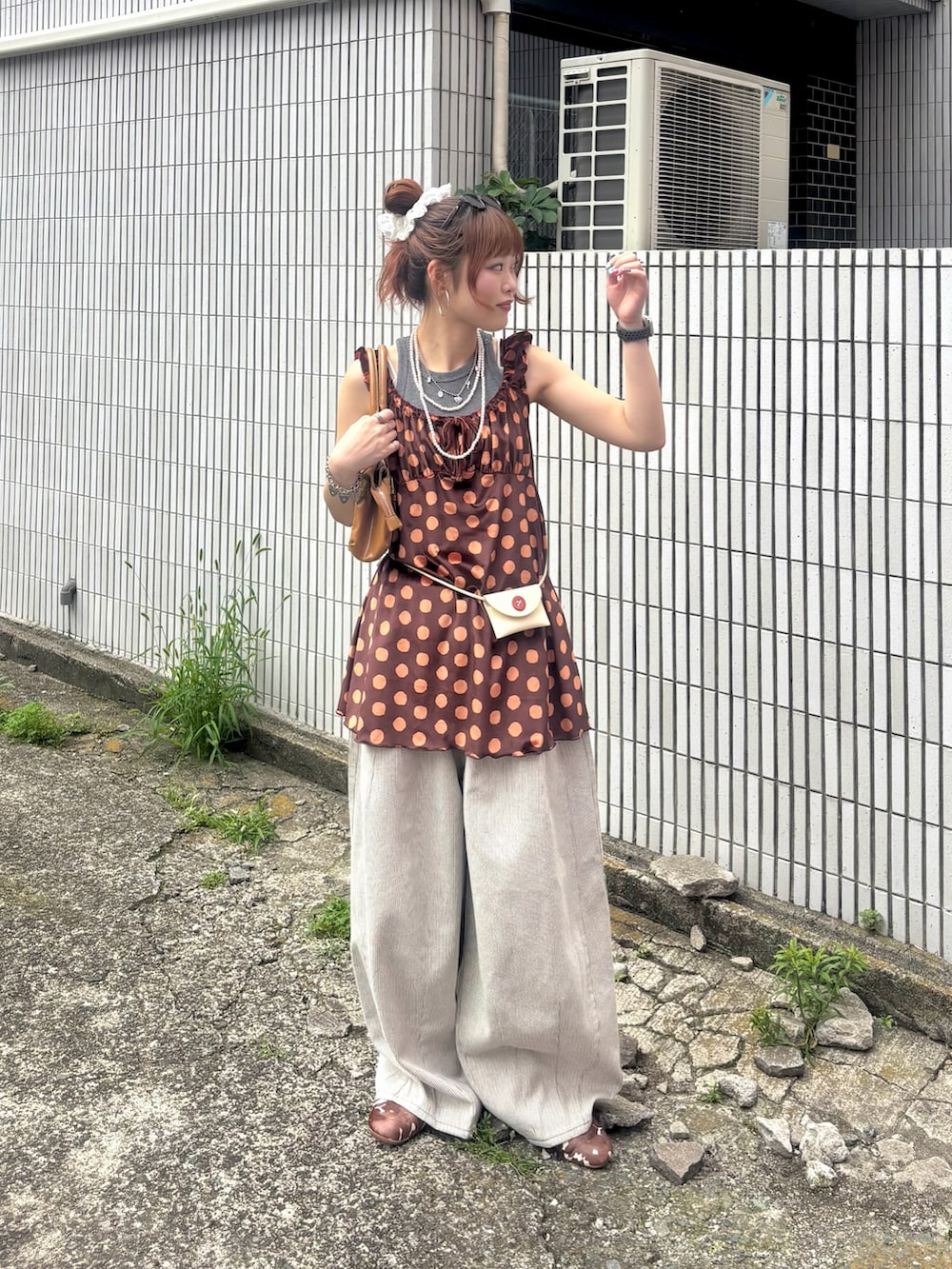 オレンジ系のチュニック、ホワイト系のボディバッグ/ウエストポーチ、ホワイト系のデニムパンツを着用したレディースの夏コーディネートの2枚目の写真