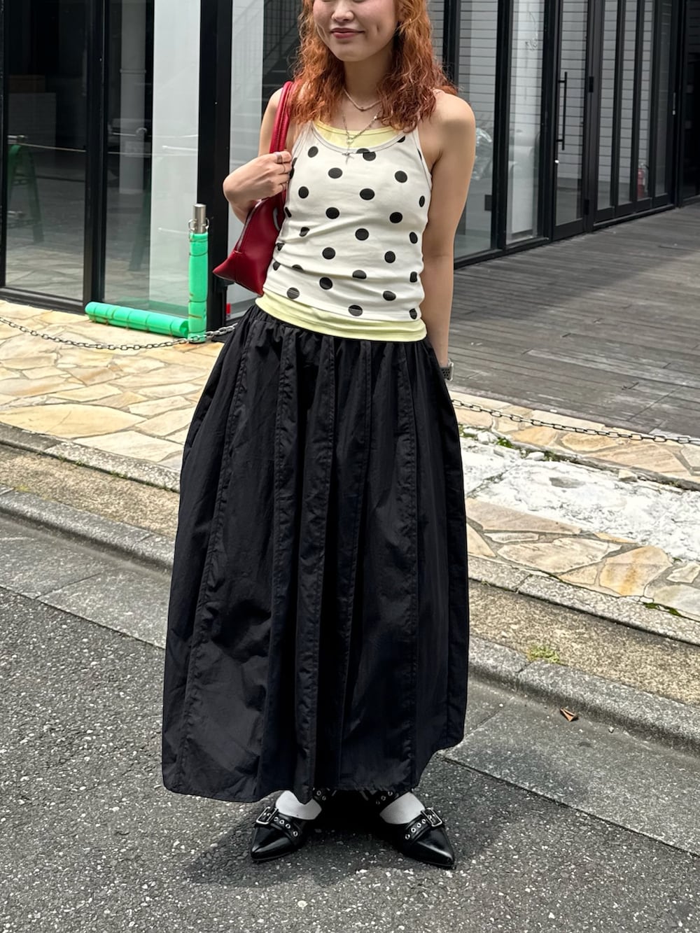 イエロー系のタンクトップ、レッド系のトートバッグ、ブラック系のスカートを着用したレディースの夏コーディネートの2枚目の写真
