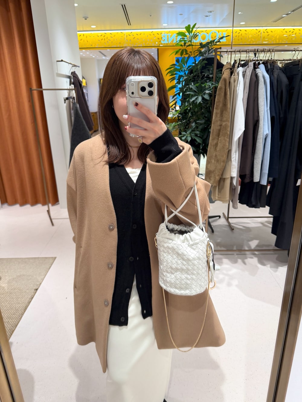 イエロー系のノーカラーコート、ホワイト系のショルダーバッグ、ブラック系のカーディガン/ボレロを着用したレディースの秋コーディネートの5枚目の写真