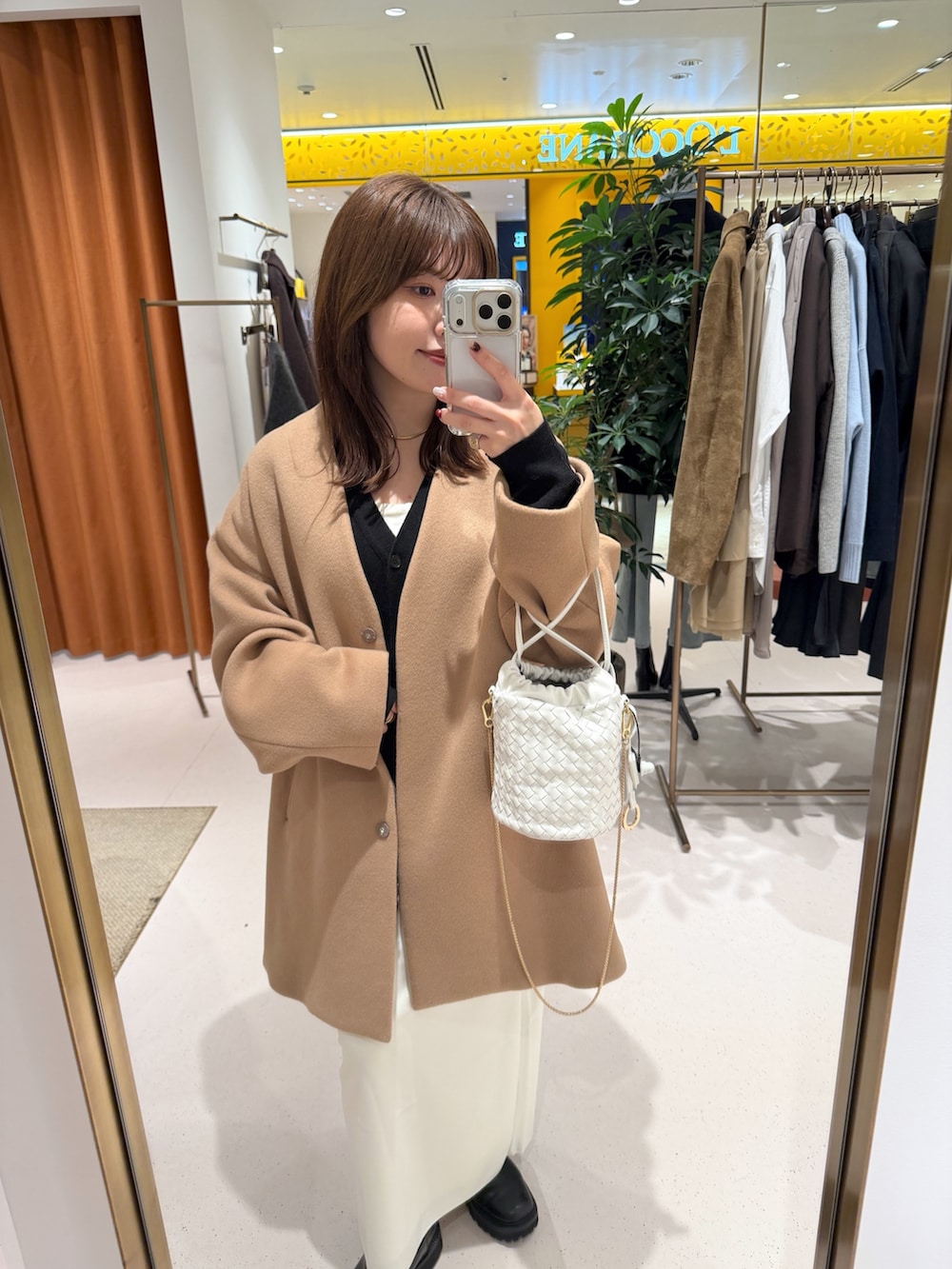 イエロー系のノーカラーコート、ホワイト系のショルダーバッグ、ブラック系のカーディガン/ボレロを着用したレディースの秋コーディネートの10枚目の写真