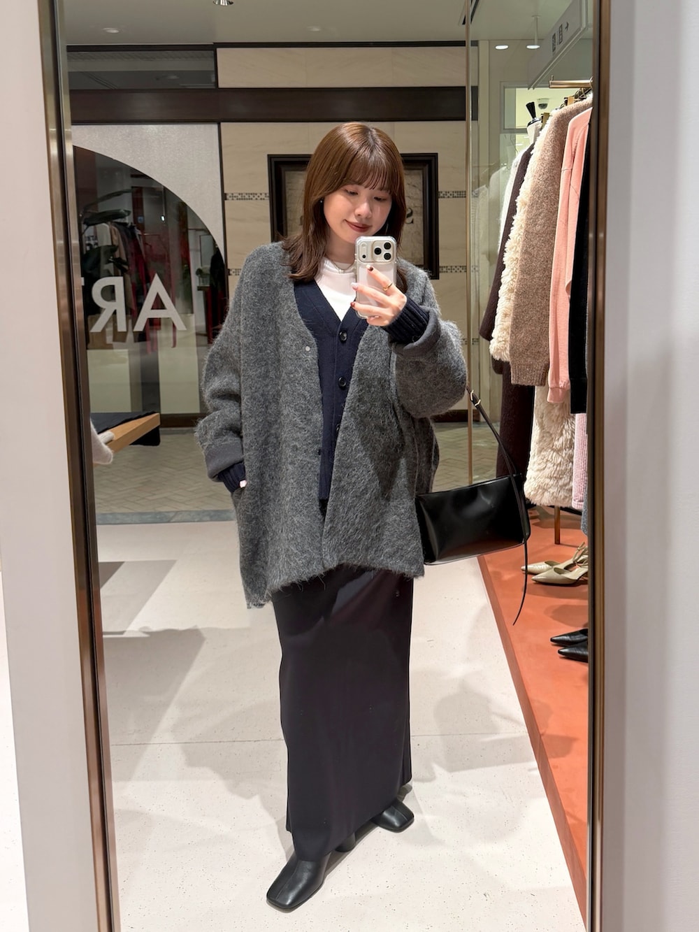 ホワイト系のTシャツ/カットソー、ブラック系のスカート、ブラック系のブーツを着用したレディースの秋コーディネートの7枚目の写真