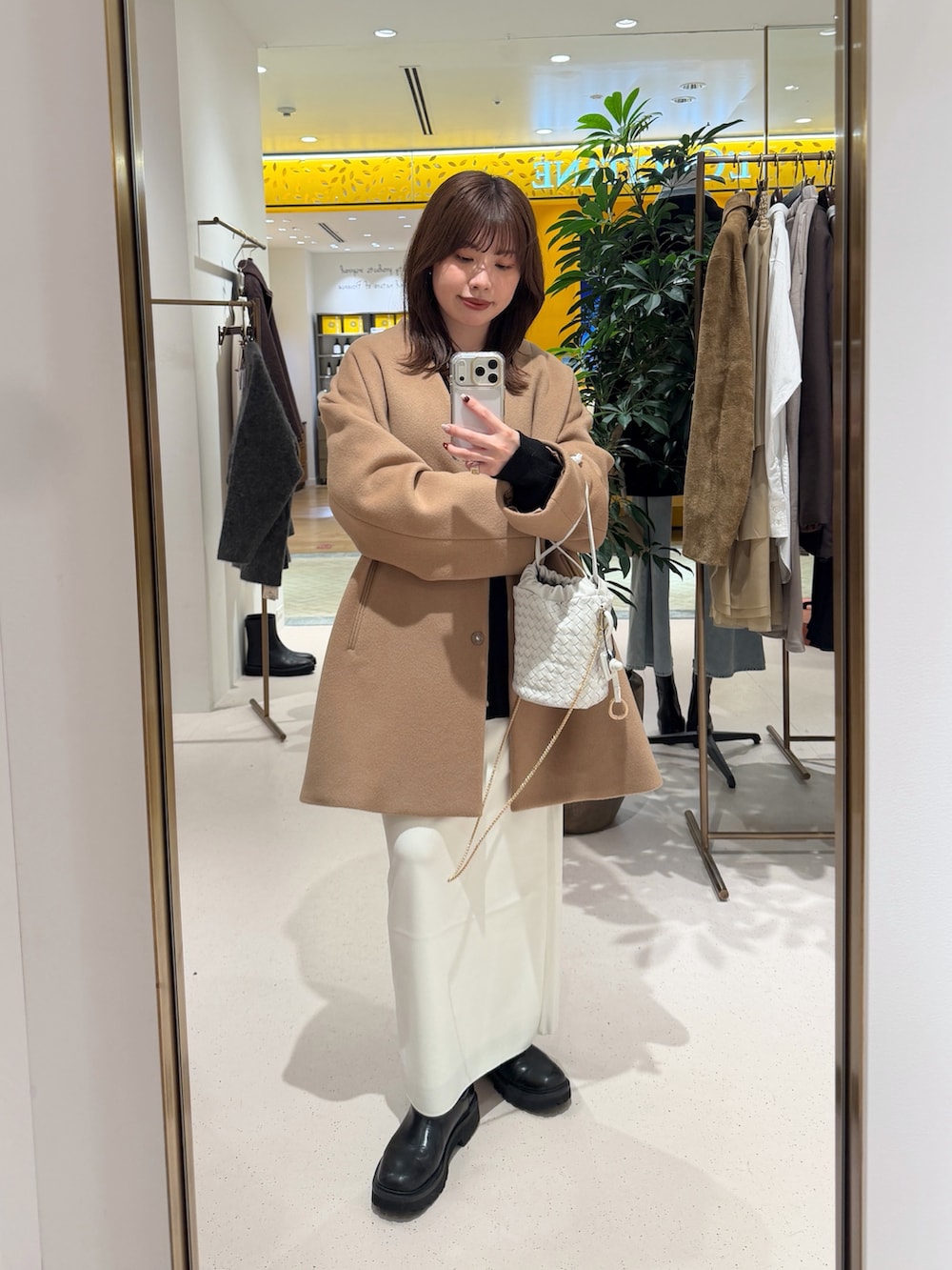 イエロー系のノーカラーコート、ホワイト系のショルダーバッグ、ブラック系のカーディガン/ボレロを着用したレディースの秋コーディネートの7枚目の写真