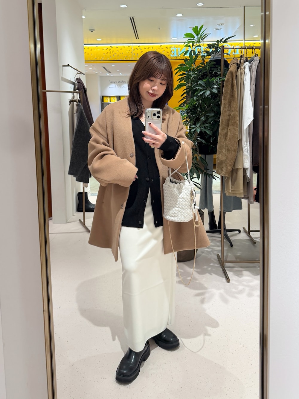イエロー系のノーカラーコート、ホワイト系のショルダーバッグ、ブラック系のカーディガン/ボレロを着用したレディースの秋コーディネートの2枚目の写真