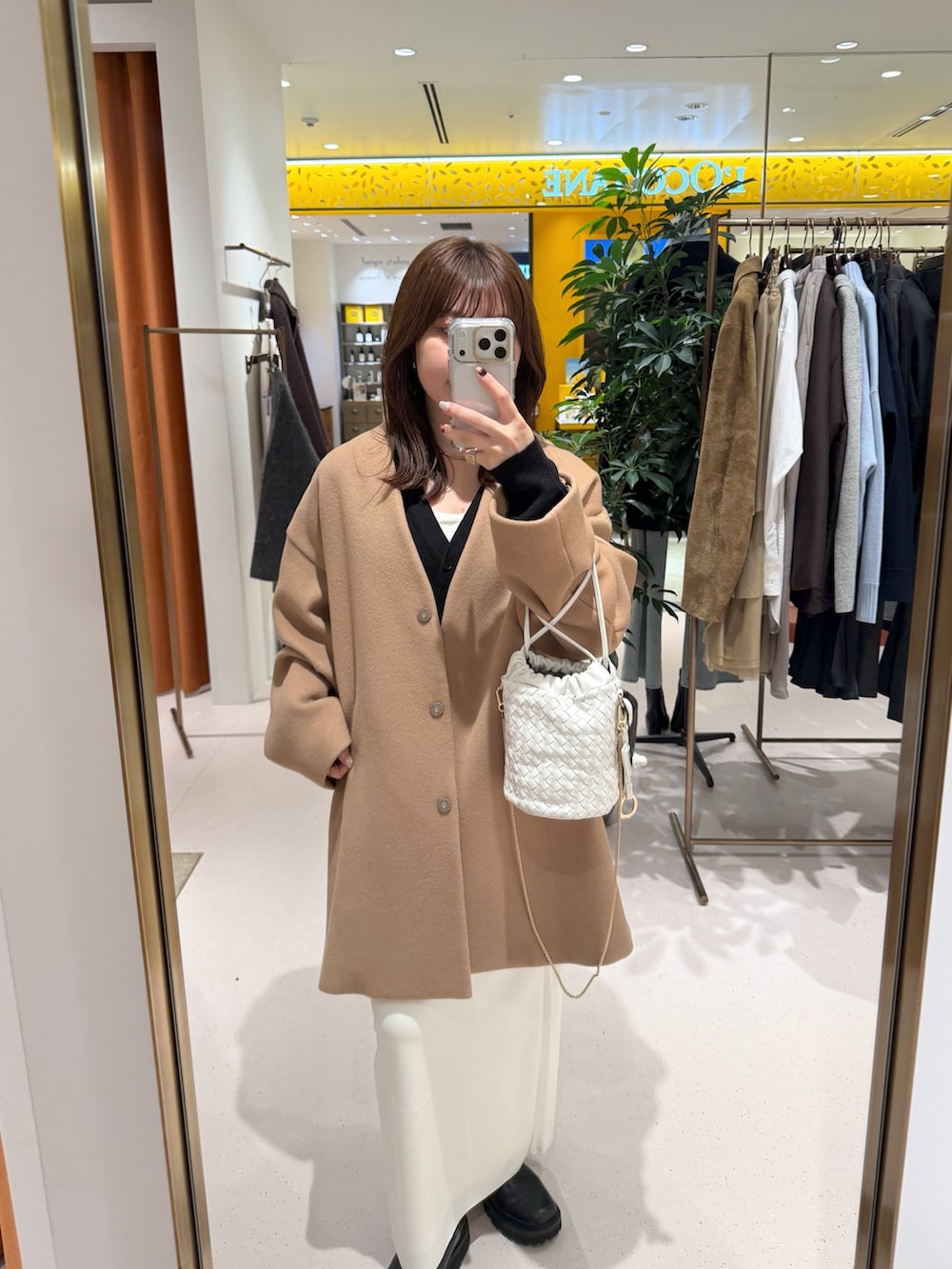 イエロー系のノーカラーコート、ホワイト系のショルダーバッグ、ブラック系のカーディガン/ボレロを着用したレディースの秋コーディネートの4枚目の写真