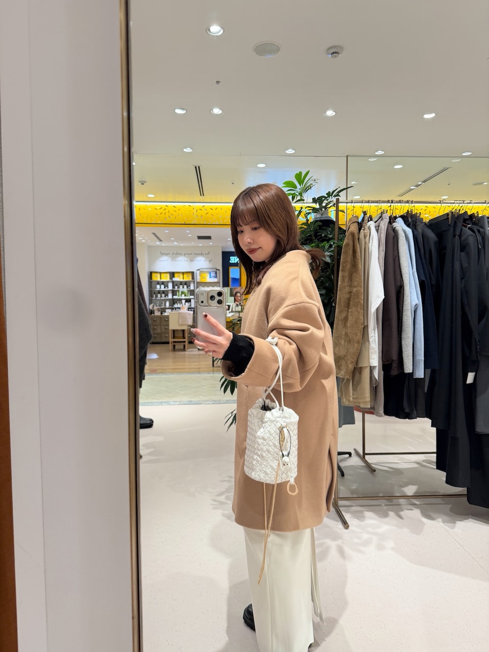 イエロー系のノーカラーコート、ホワイト系のショルダーバッグ、ブラック系のカーディガン/ボレロを着用したレディースの秋コーディネートの9枚目の写真