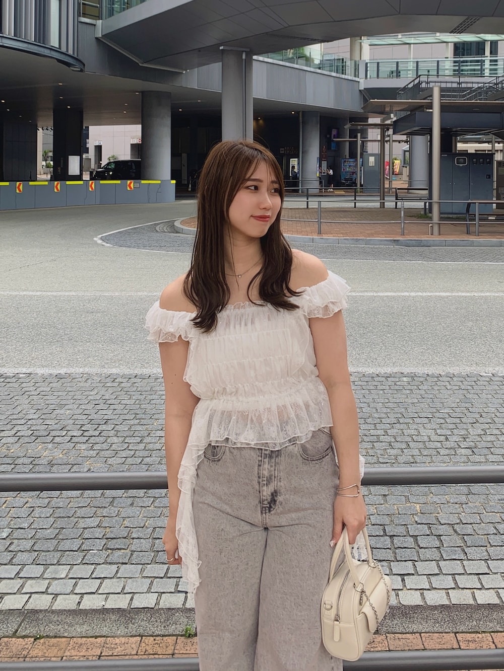 ピンク系のデニムパンツ、ホワイト系のサンダル、ホワイト系のボストンバッグを着用したレディースの夏コーディネートの2枚目の写真