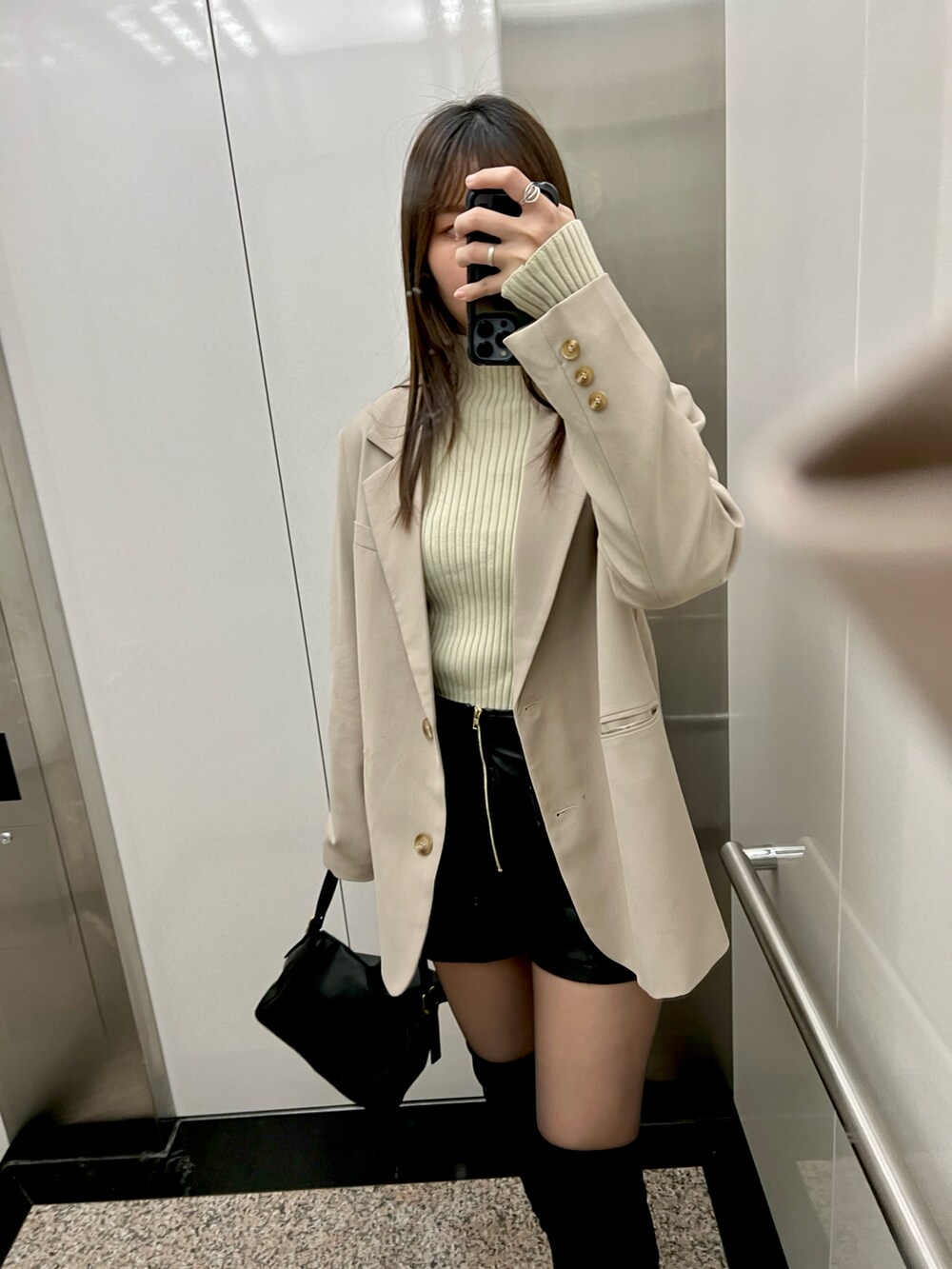 ベージュ系のニット/セーター、ブラック系のブーツを着用したレディースの冬コーディネートの2枚目の写真