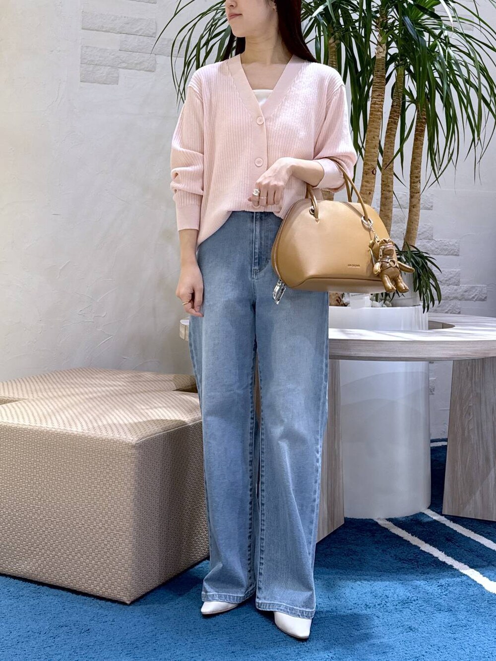 ブルー系のデニムパンツ、ブラウン系のトートバッグ、ホワイト系のキャミソールを着用したレディースの冬コーディネートの4枚目の写真