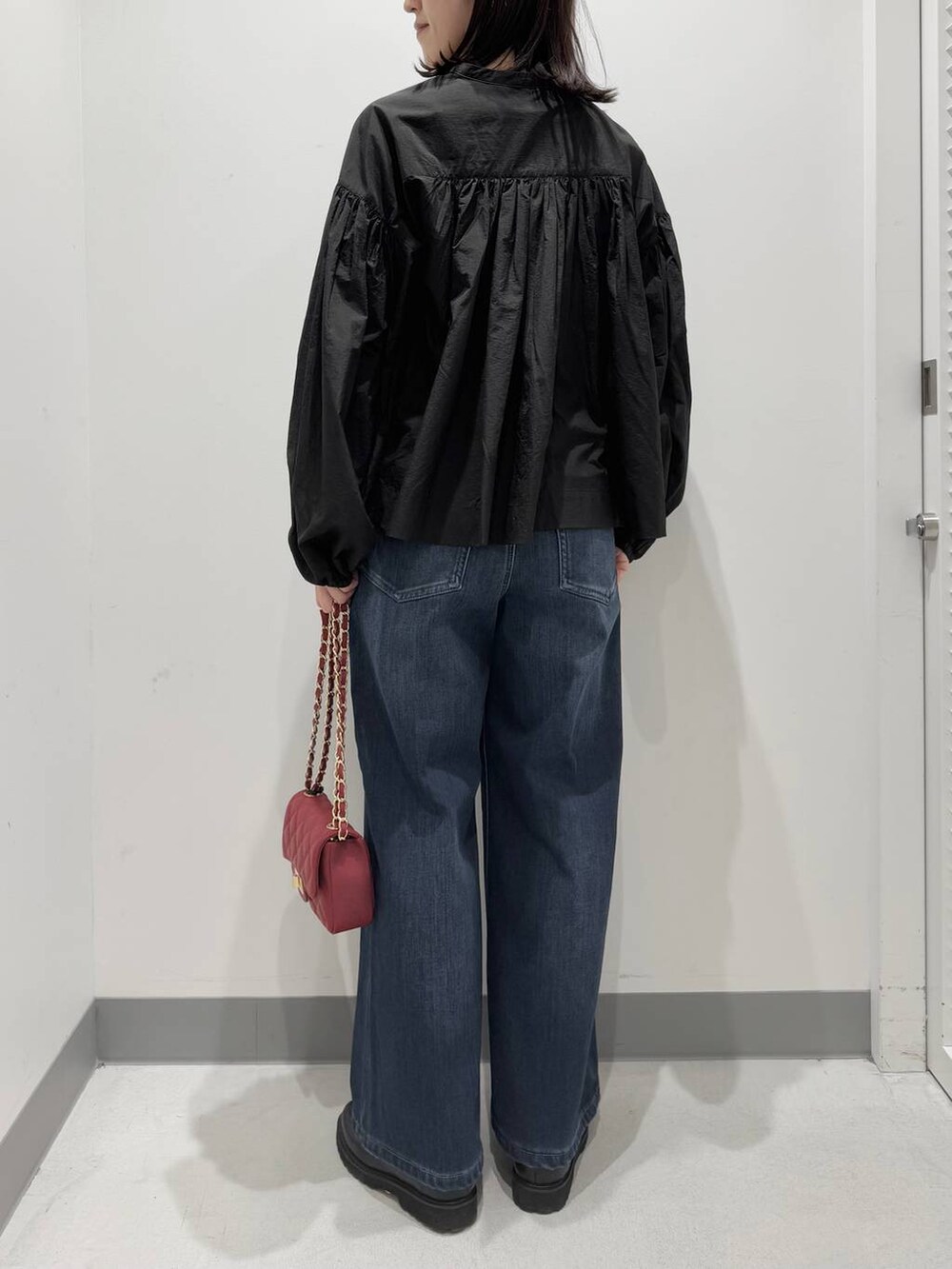 ブルー系のデニムパンツ、ブラック系のローファー、レッド系のハンドバッグを着用したレディースの冬コーディネートの3枚目の写真