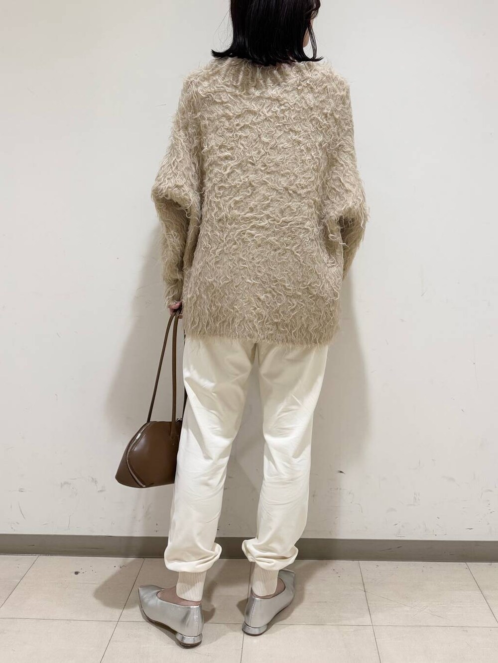 イエロー系のトートバッグ、シルバー系のパンプス、ベージュ系のカーディガン/ボレロを着用したレディースの冬コーディネートの3枚目の写真