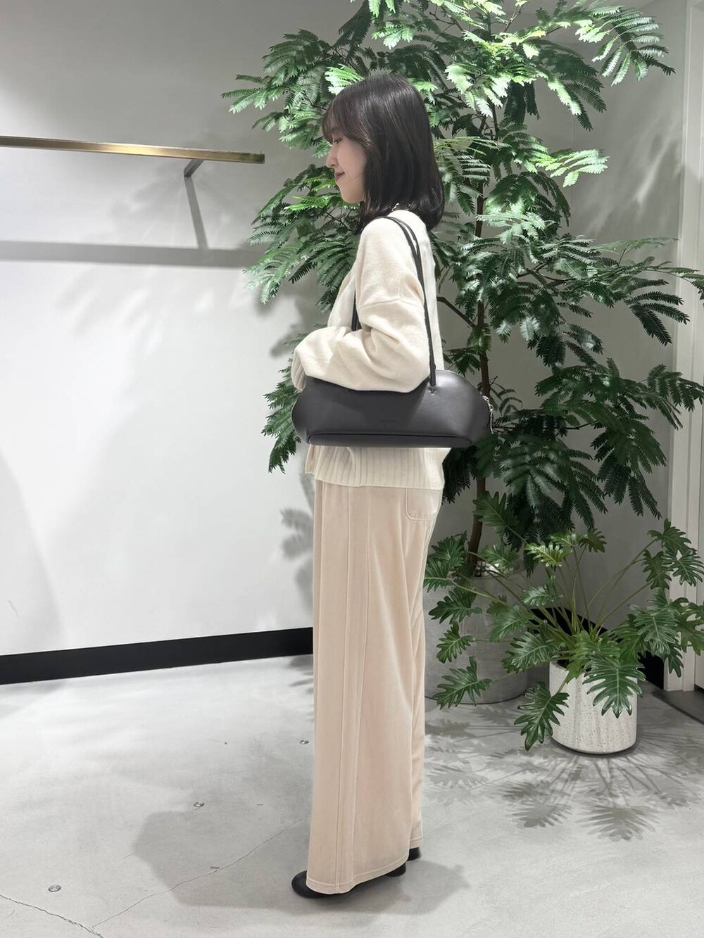 ブラック系のトートバッグ、ブラック系のブーツ、ホワイト系のニット/セーターを着用したレディースの冬コーディネートの2枚目の写真