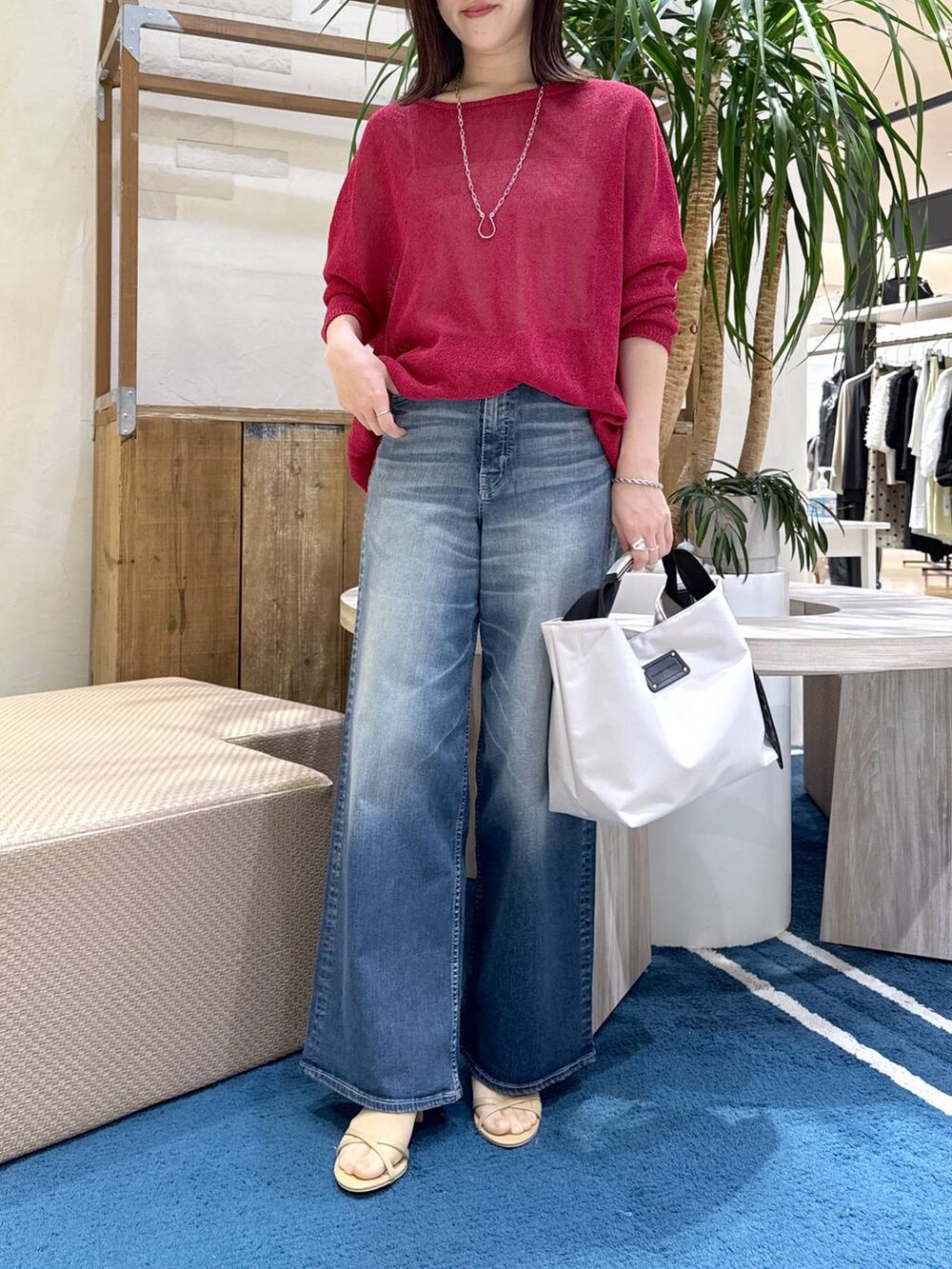 ホワイト系のトートバッグ、ブルー系のデニムパンツ、レッド系のニット/セーターを着用したレディースの春コーディネートの5枚目の写真