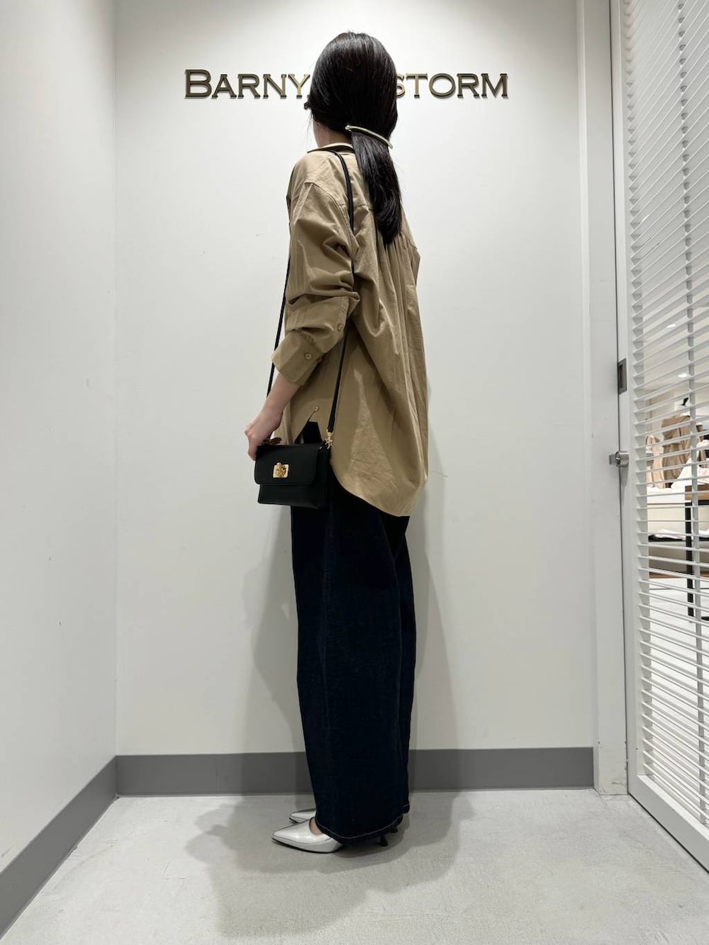 シルバー系のパンプス、ブルー系のデニムパンツ、ブラック系のショルダーバッグを着用したレディースの冬コーディネートの2枚目の写真