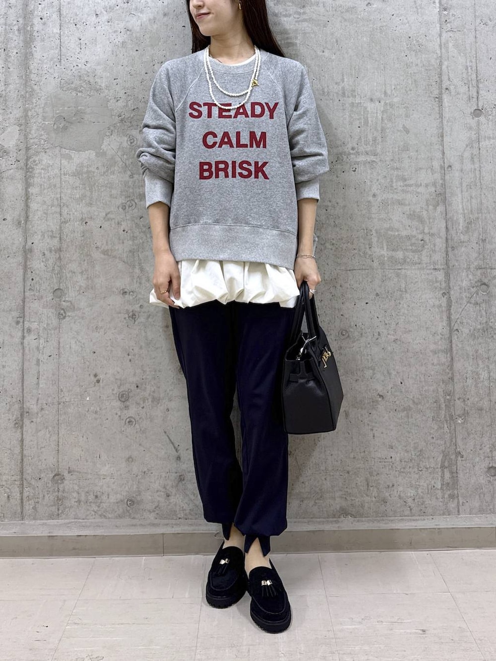 ブラック系のショルダーバッグ、グレー系のスウェット、ホワイト系のTシャツ/カットソーを着用したレディースの秋コーディネートの2枚目の写真