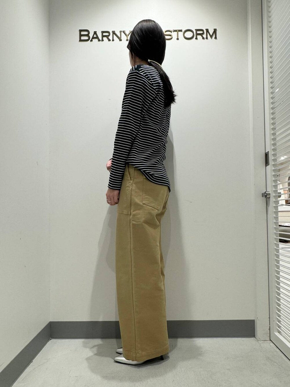 シルバー系のパンプス、ベージュ系のその他パンツ、ブラック系のショルダーバッグを着用したレディースの冬コーディネートの2枚目の写真