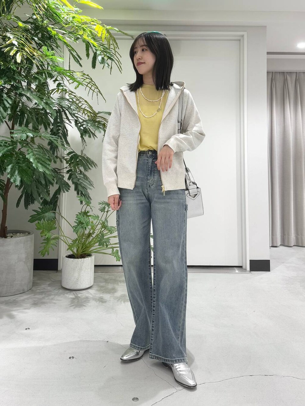 シルバー系のハンドバッグ、シルバー系のローファー、ブルー系のデニムパンツを着用したレディースの冬コーディネートの2枚目の写真